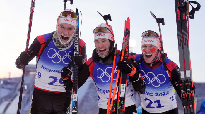 Christian Gow, center, and Scott Gow, right, celebrate after the men's 15-kilometer biathlon.
